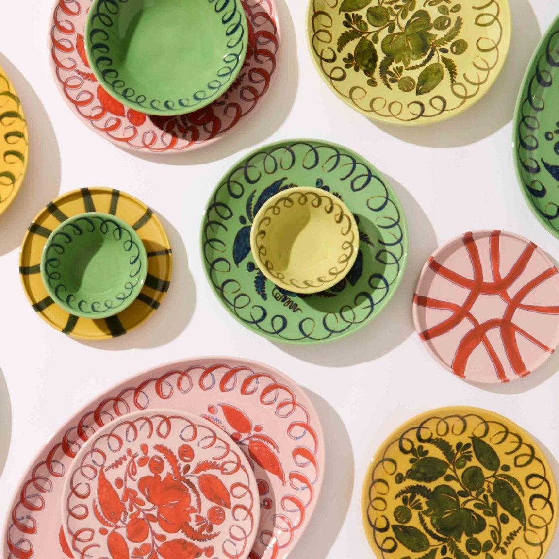 Collection of colorful ceramic plates with various patterns on a white background.