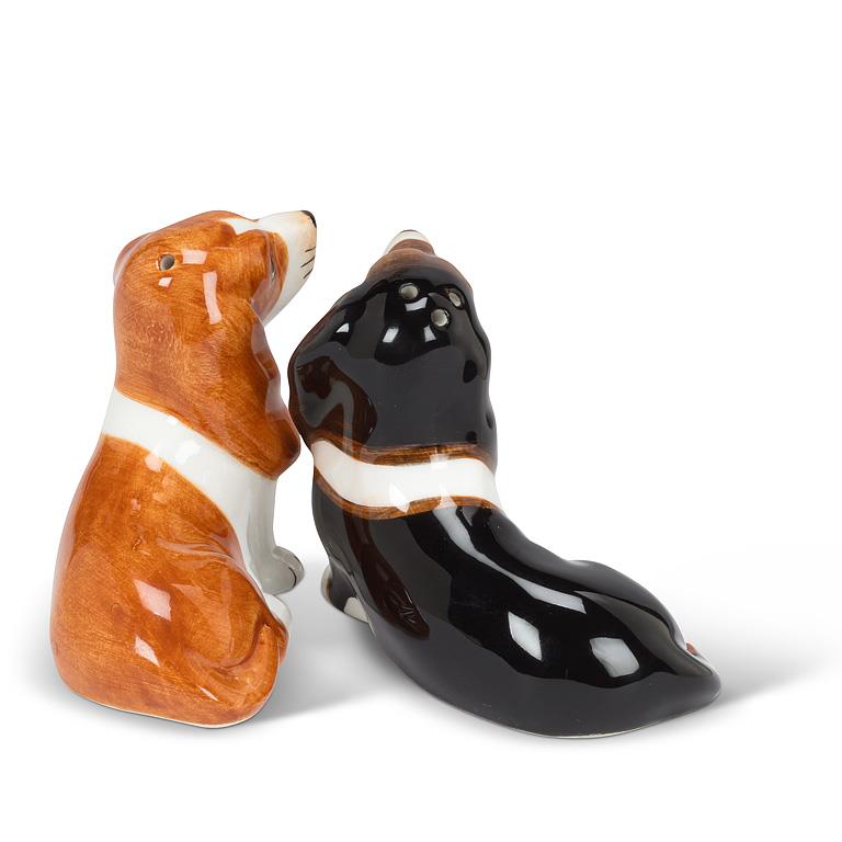 Two ceramic basset hound salt and pepper shakers, one with a brown and white coat and the other with a glossy black and white coat, set against a plain white background.