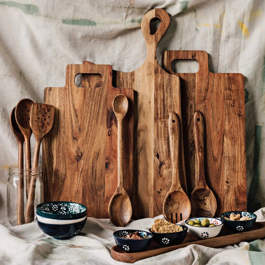 Set of wooden cutting boards and spoons on a textured fabric background.