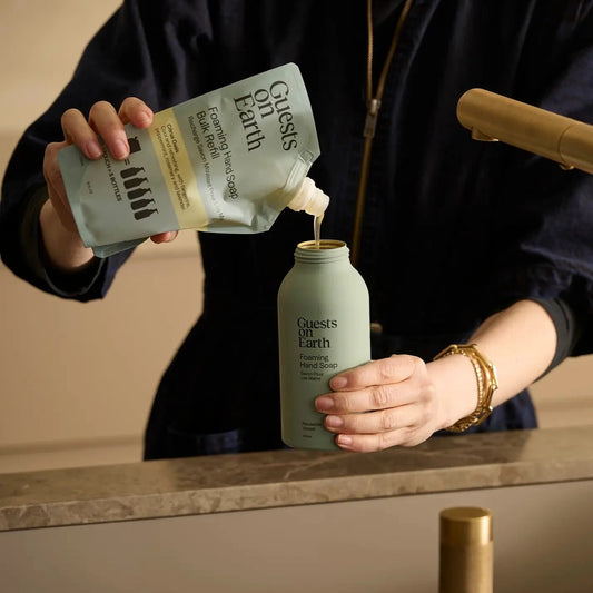 Person pouring a product from a labeled bag into a bottle on a kitchen counter.