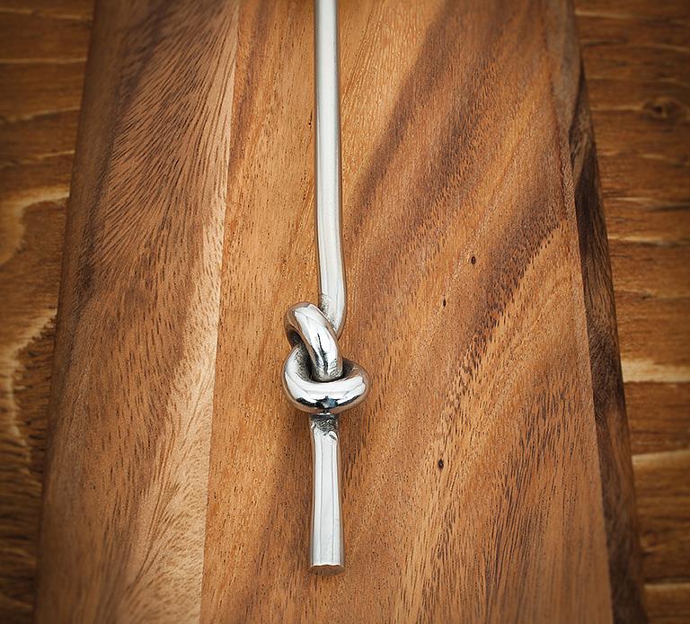 Chrome knot detail of a utensil handle.