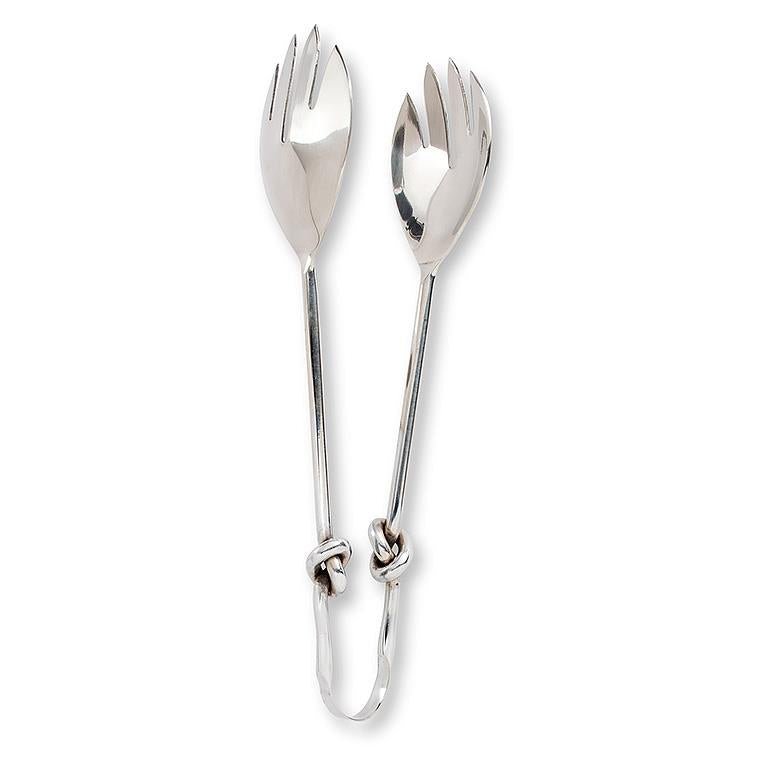 Pair of chrome knot salad servers on a white background.