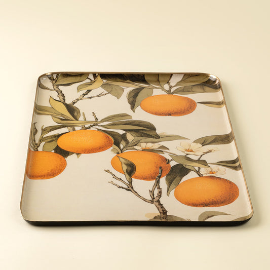 A square decorative tray with rounded corners featuring a botanical print of oranges on a tree with green leaves and white blossoms, set against a solid cream background.