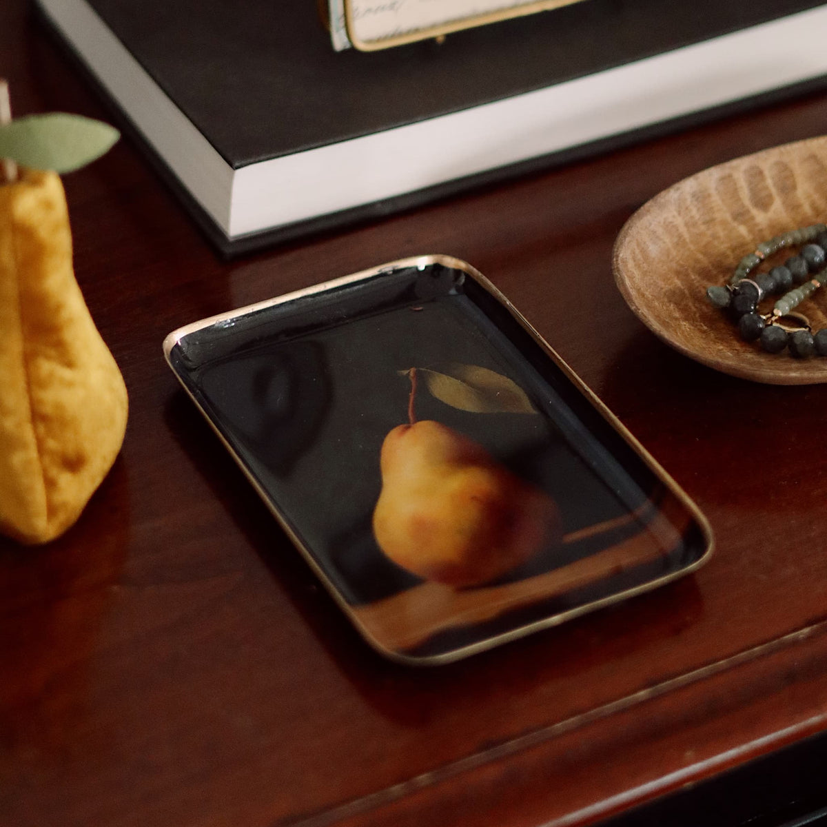 Pear on a dark plate with a notebook in the background on a wooden surface.