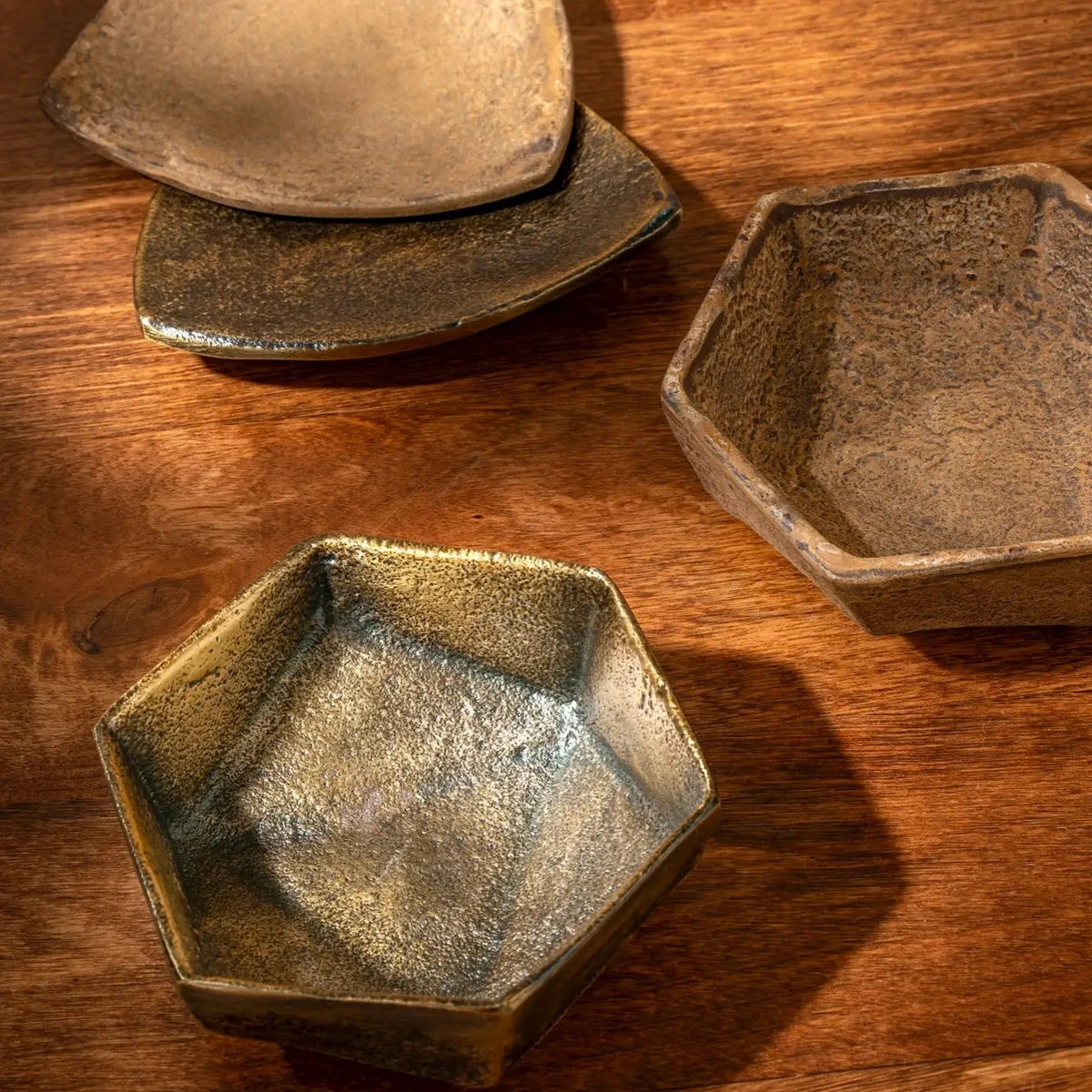 Three metal bowls of different shapes with rusty patina, on a wooden surface.
