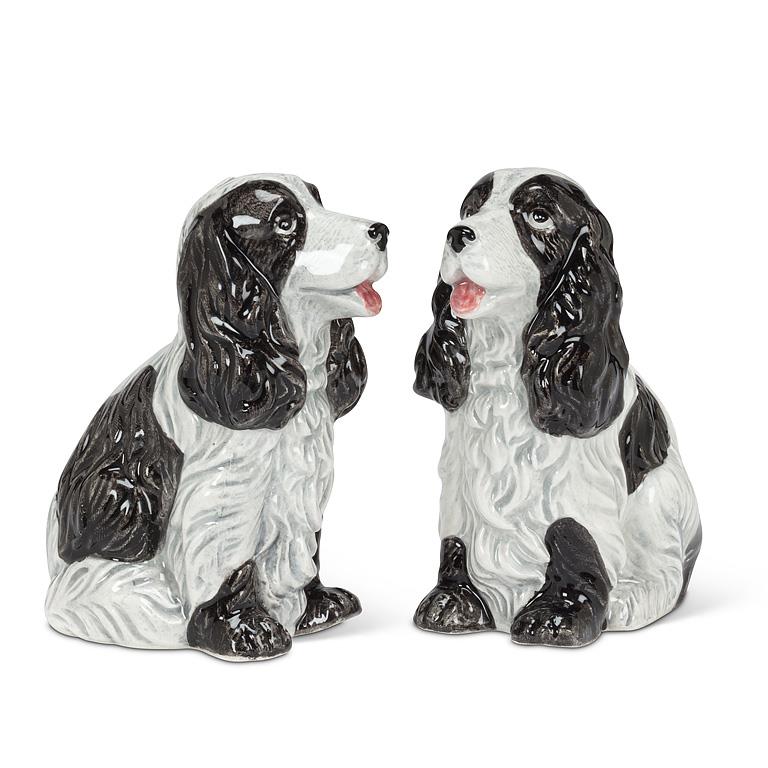 A pair of ceramic salt and pepper shakers shaped like sitting black and white spaniel dogs, shown on a plain white background.