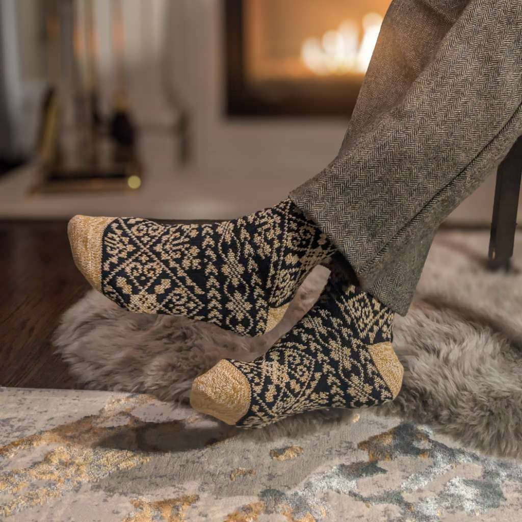 Person wearing patterned socks in a cozy living room with a fireplace.