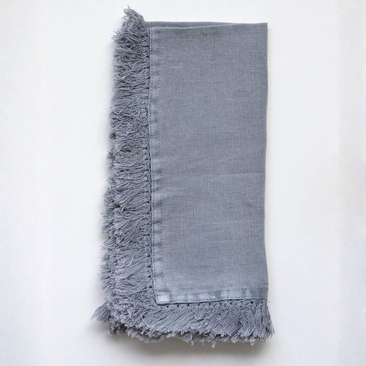 A folded light gray linen napkin with fringed edges, displayed flat against a clean white background.