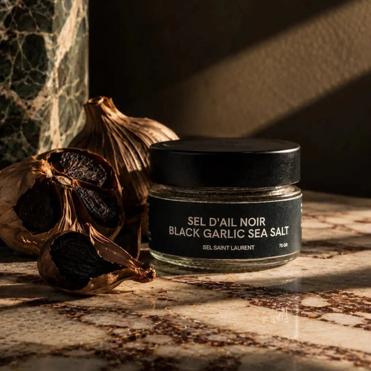 Black Garlic Sea Salt bottle on marble countertop and dark background.