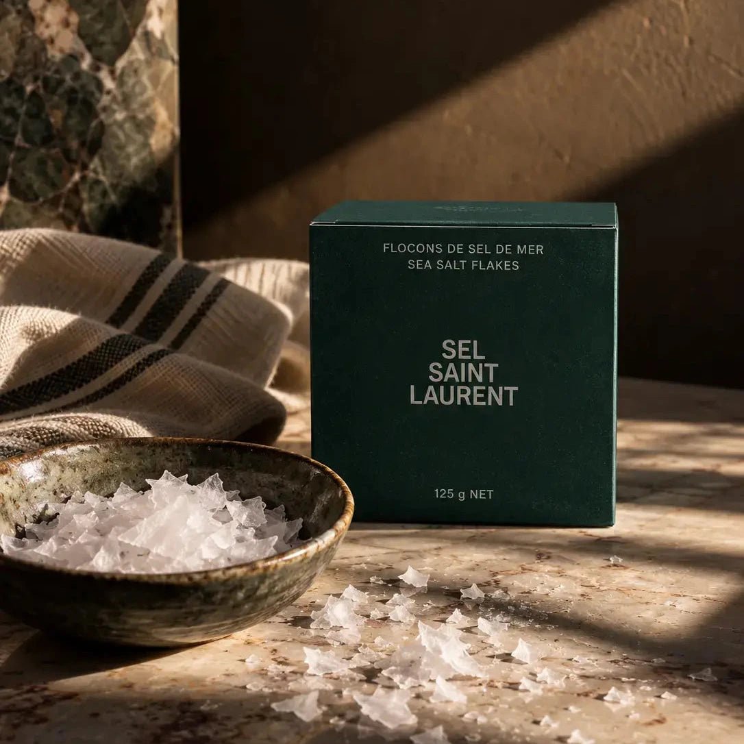 Hand-Harvested Québec Sea Salt Flakes in dark green box, on a marble countertop and dark background.