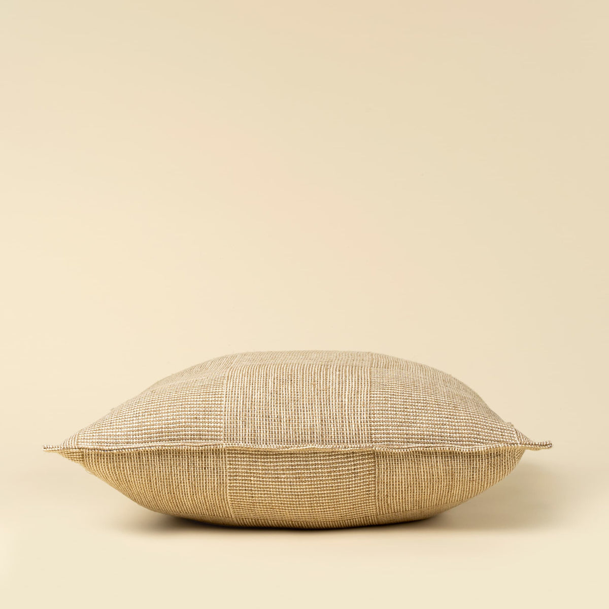 A square throw pillow with a textured, woven flax linen fabric in a warm cream and beige color, shown against a solid cream background.
