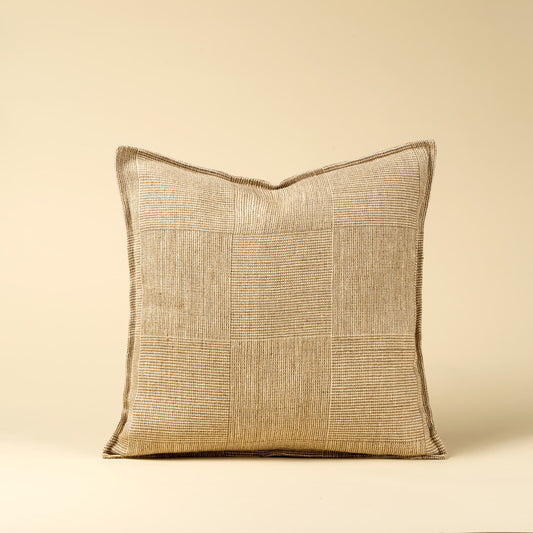 A square throw pillow with a textured, woven patchwork-style flax linen fabric in a warm cream and taupe colour, shown against a solid cream background.