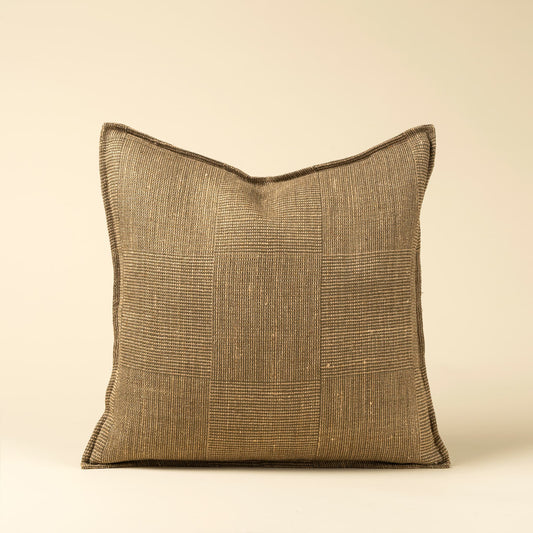 A square throw pillow with a textured, woven patchwork-style flax linen fabric in a warm olive and taupe color, shown against a solid cream background.