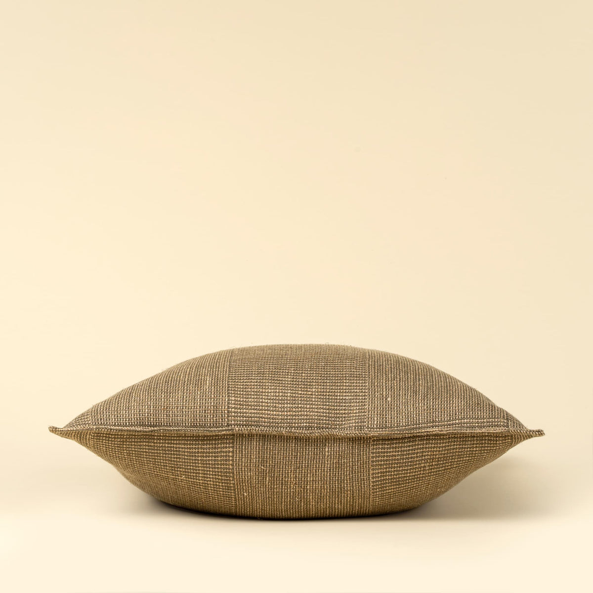 A square throw pillow with a textured, woven flax linen fabric in a warm taupe-brown color, shown against a solid cream background.