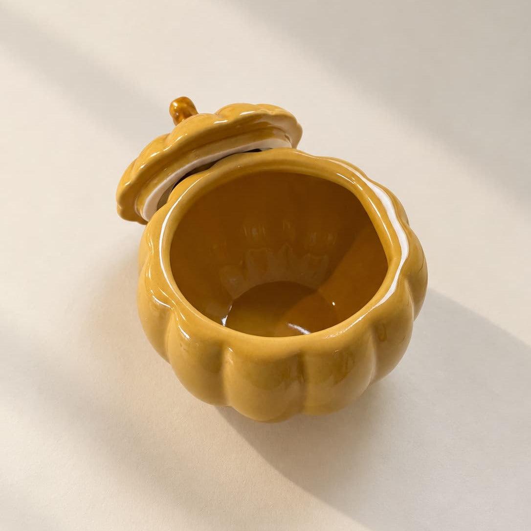 Ochre-coloured ceramic pumpkin-shaped soup bowl with lid open, on a white background.
