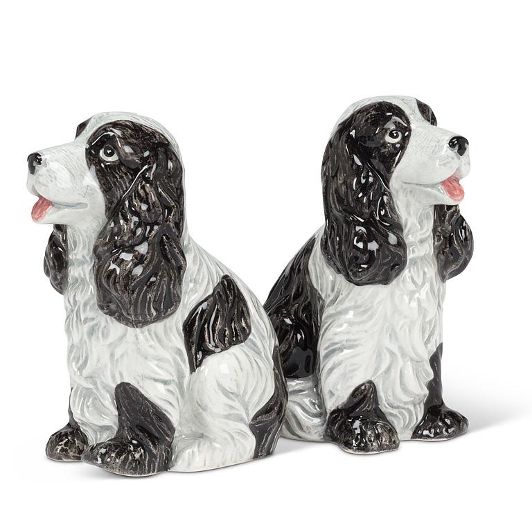 A pair of glossy ceramic dog figurines shaped like black and white spaniel dogs, shown on a plain white background.