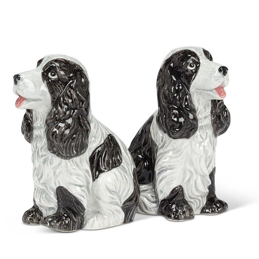 A pair of glossy ceramic dog figurines shaped like black and white spaniel dogs, shown on a plain white background.