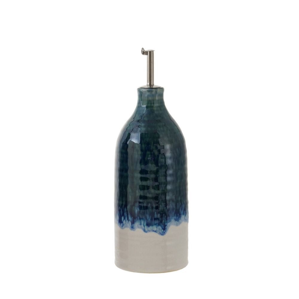 A ceramic oil bottle with a glossy glaze featuring a dark blue glazed upper body that drips into a white lower body, topped with a silver metal pour spout, on a white background.