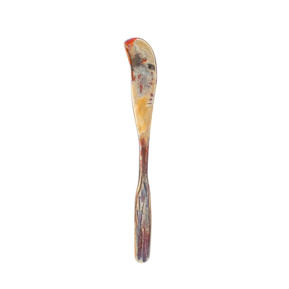 A single sculptural copper spreader with a curved handle on a white background.
